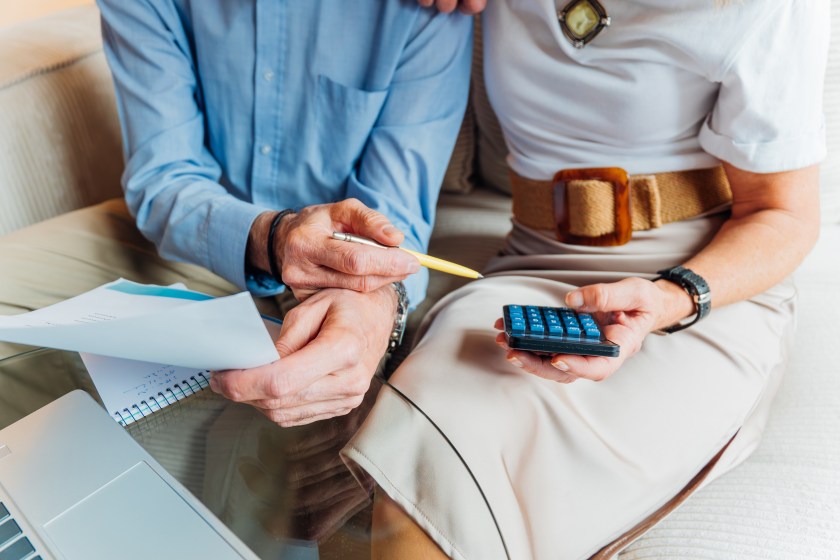 Elderly couple managing household finances and retirement planning, calculating expenses and reviewing bills on a laptop, stressing budget and financial consulting for seniors.