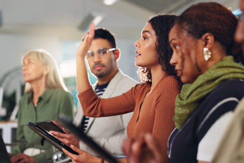 Group of employees, one raising hand
