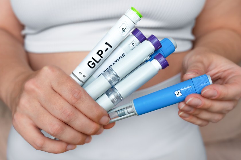 Woman holding multiple GLP-1 injection pens, weight loss and diabetes treatment concept.