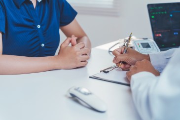Doctor examining patient symptoms, providing healthcare advice in office, discussing diagnosis and treatment plan for wellness.