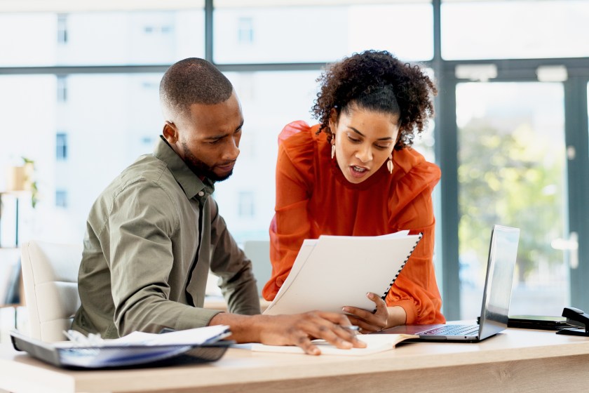 Two employees looking at paperwork, choosing, talking
