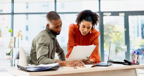 Two employees looking at paperwork, choosing, talking