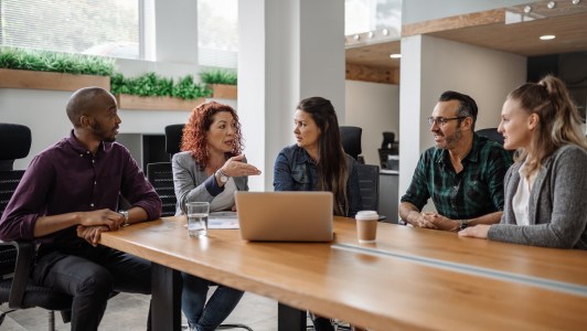 Group of employees sitting at table, talking