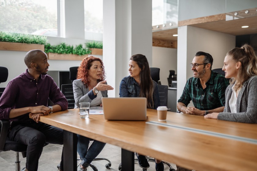 Group of employees sitting at table, talking
