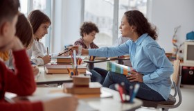 Teacher sitting with students, helping