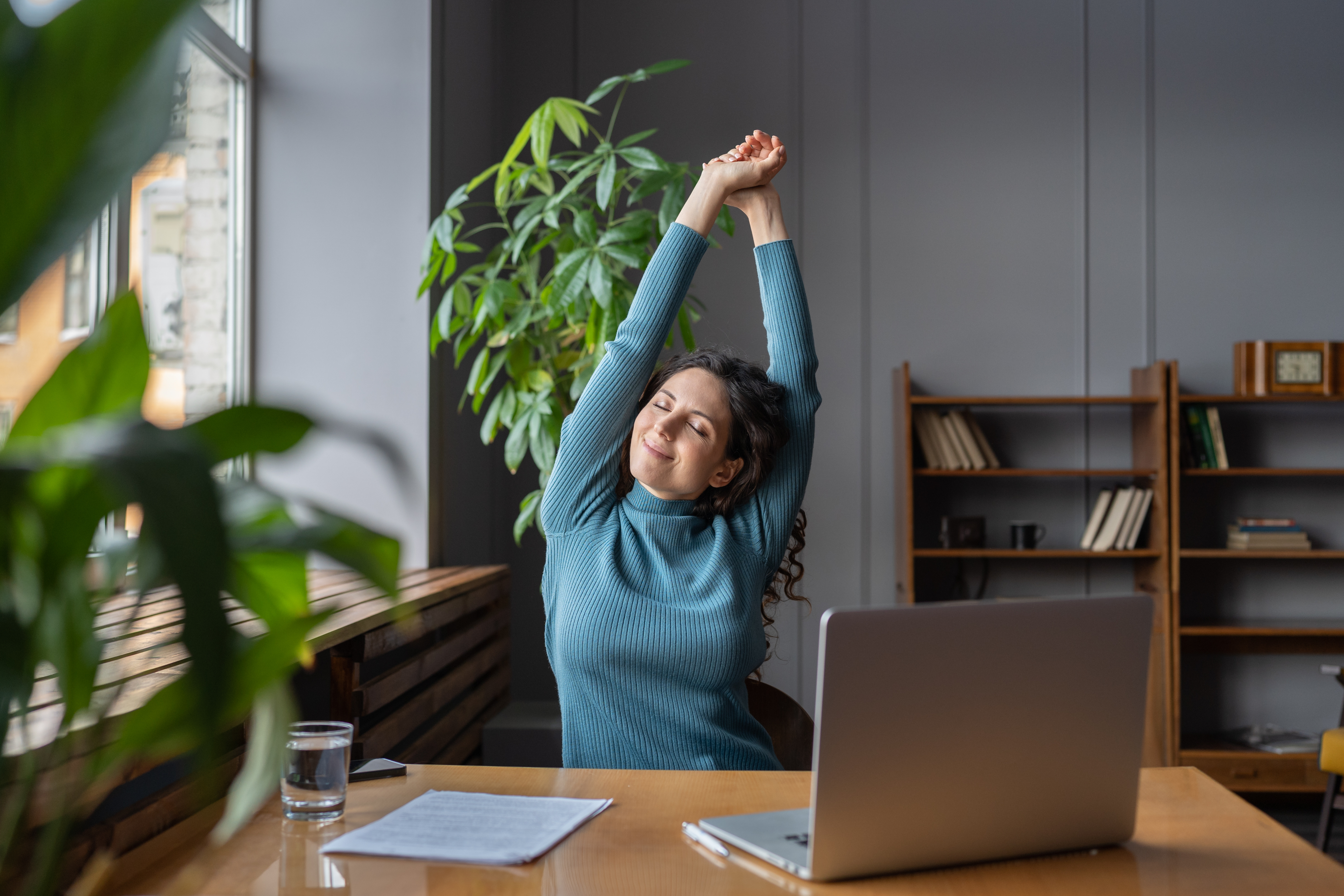 Woman stretching at desk, looking at peace