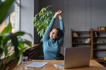 Woman stretching at desk, looking at peace
