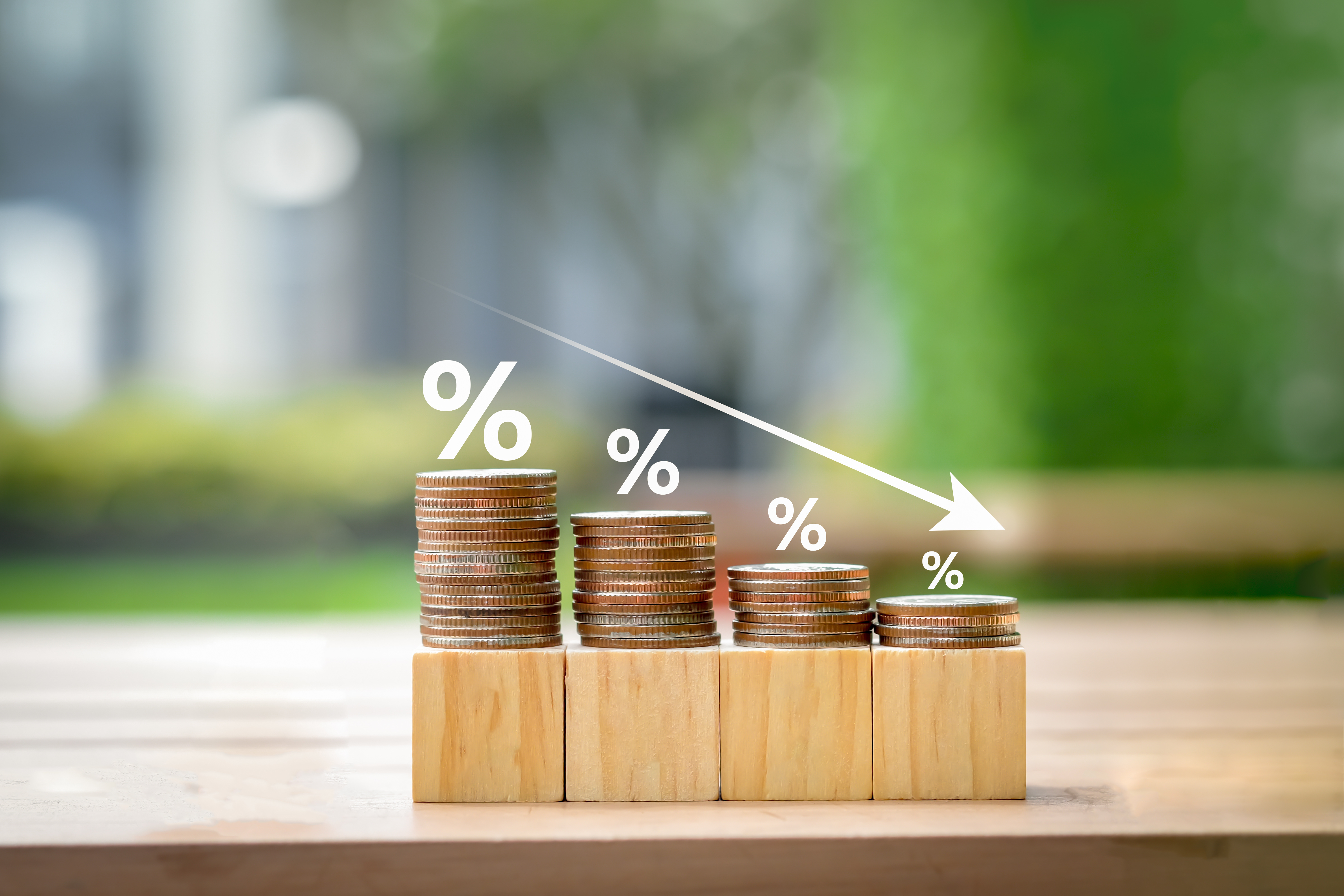 Low interest rates. Percentage sign on different high of coins stack and arrow going down.